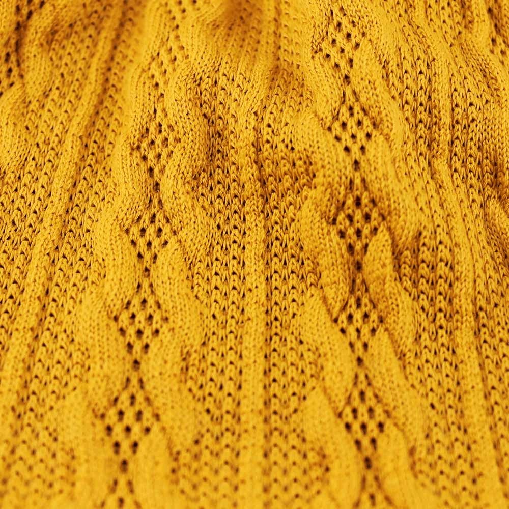 Close-up of mustard yellow knit fabric with a wavy pattern, showing texture and craftsmanship.